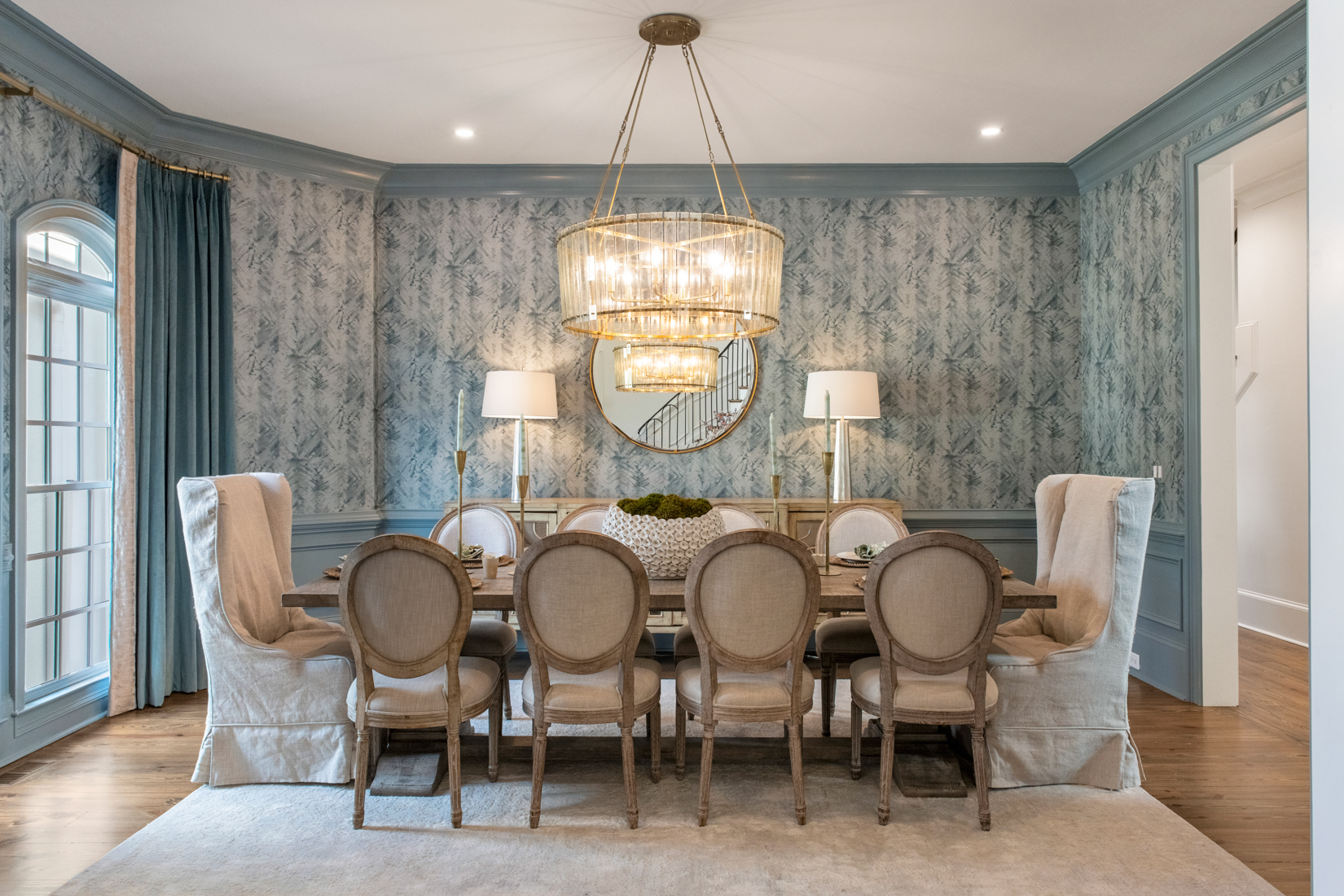 A beautifully set dining table with elegant chairs, lighting, and gathered seating